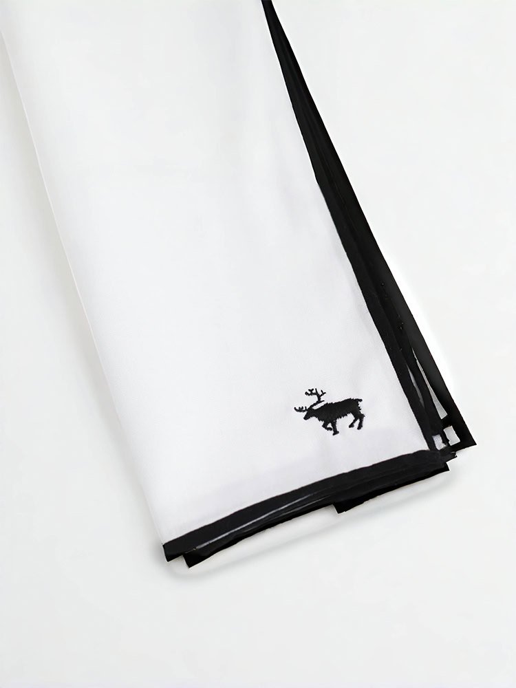 A hand - rolled hem cotton pocket square featuring a small fawn emblem
