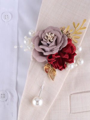 Burgundy and mauve rose brooch with gold - toned accents and pearl details on a lapel