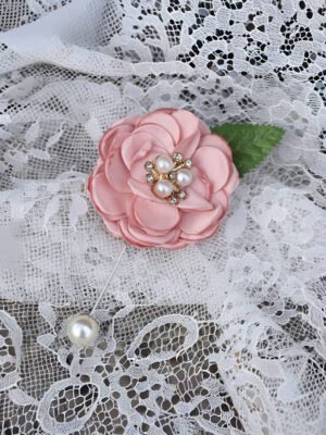 Pink camellia brooch with pearl accents on white lace