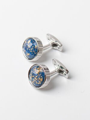 A pair of circular silver - and - gold cufflinks with a cosmic blue design.