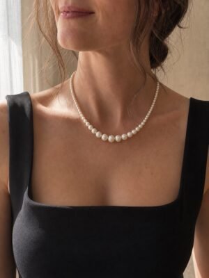 Woman wearing a graduated freshwater pearl necklace with a black square-neck top