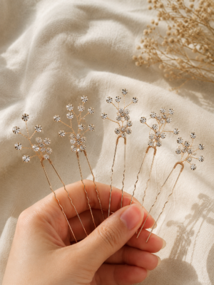 Gold five-piece floral bridal hair pin set with clear crystal-style accents held in hand