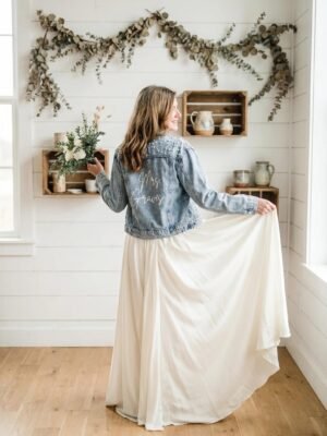 Custom pearl bridal denim jacket styled with a white wedding dress and personalized back lettering