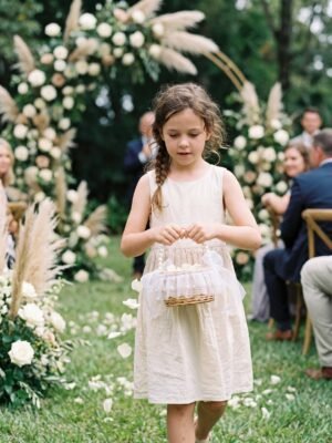 Ivory pearl flower girl basket in a garden wedding ceremony
